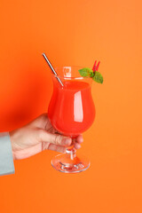 Woman with glass of refreshing cocktail on orange background, closeup