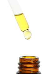 Dripping tincture from pipette into bottle on white background, closeup
