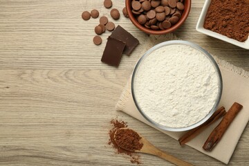 Flour, chocolate and cocoa for making dough on wooden table, flat lay. Space for text
