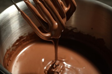 Chocolate dough dripping from mixer into bowl, closeup