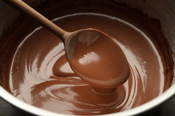 Chocolate dough dripping from spoon into bowl, closeup