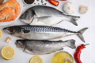 Fresh raw sea food and products on white tiled table, flat lay