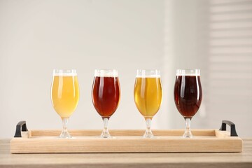 Glasses with different types of beer on wooden table indoors