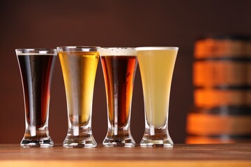 Glasses with different types of beer on wooden table in bar, closeup