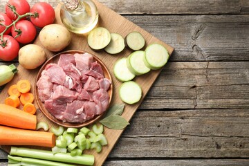 Cooking stew. Uncooked meat and vegetables on wooden table, top view. Space for text