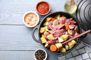 Cooking stew. Uncooked meat and vegetables in pot on light grey wooden table, flat lay. Space for text