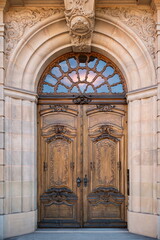 Large, old, sculpted and decorated hardwood entrance door in a European city, no people
