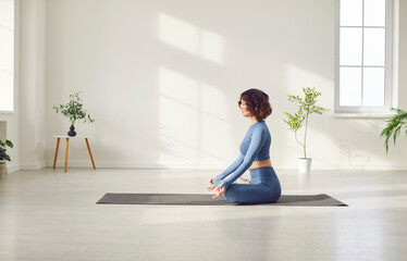 Yogi sporty attractive woman practicing yoga, doing Padmasana exercise, meditating in Lotus pose...