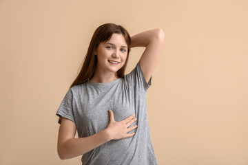 Young woman checking her breast on beige background