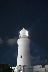 星空広が広がる夜と灯台の光