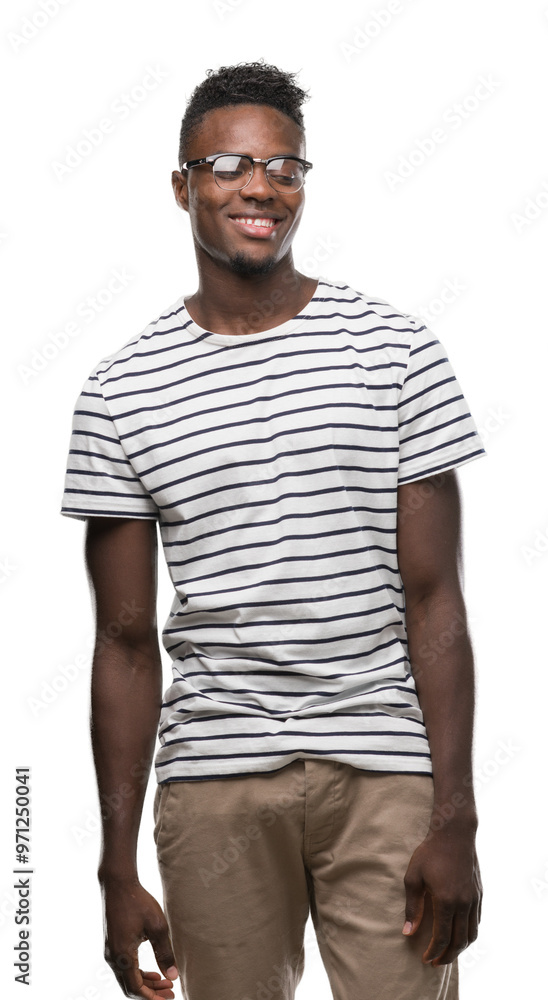 Sticker Young african american man wearing glasses and navy t-shirt looking away to side with smile on face, natural expression. Laughing confident.