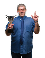 Handsome senior successful man holding trophy over isolated background surprised with an idea or...