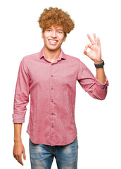 Young handsome business man with afro hair smiling positive doing ok sign with hand and fingers. Successful expression.