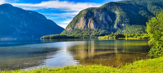 A serene lake near Hallstatt, Austria, reflecting the surrounding mountains and lush greenery, with clear skies and calm waters creating a picturesque scene. Perfect for nature lovers and outdoor enth
