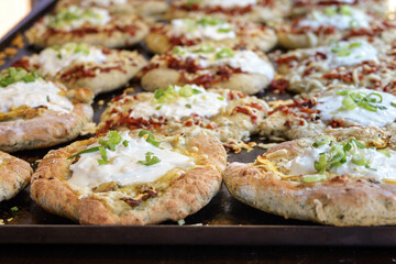 Baking tray with fresh hot langos, Hungarian flatbread variously filled with mushrooms or bacon and...
