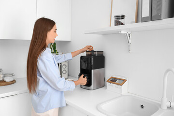 Beautiful young happy woman making coffee with machine at kitchen in office