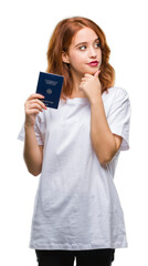 Fototapeta premium Young beautiful woman holding passport of germany over isolated background serious face thinking about question, very confused idea