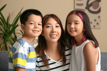 Beautiful young happy Asian mother hugging with her cute little children at home