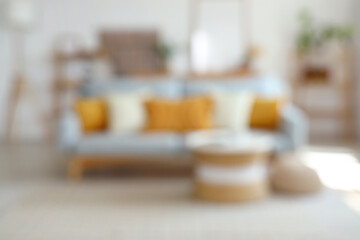 Interior of modern light living room with sofa and table, blurred view