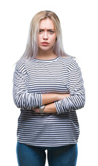 Young blonde woman over isolated background skeptic and nervous, disapproving expression on face with crossed arms. Negative person.