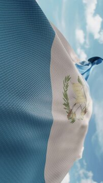 Wavy flag of Guatemala blowing in the wind in slow motion. Waving colorful Guatemalan flag team symbol abstract vertical background. Blue sky with clouds. World countries flying flags concept