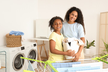 African-American woman and her daughter with laundry at home