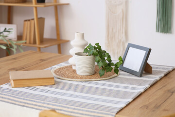 Book, houseplant and vase on wooden table in dining room