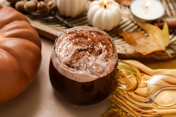 Autumn composition with cup of cocoa, scarf and decorative pumpkin on beige background, closeup