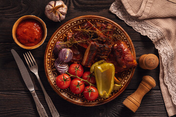 Grilled pork ribs with vegetables on dark wooden background