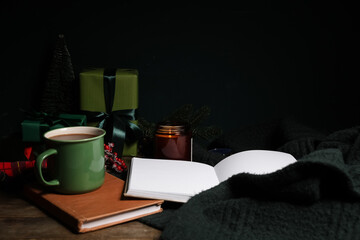Winter composition with books, Christmas gift boxes, cup of tea and warm sweater on brown wooden background