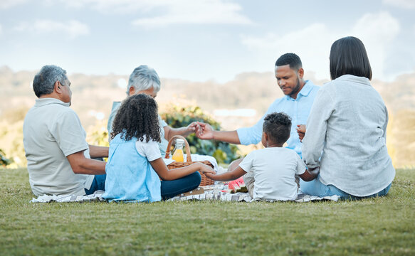 Holding hands, picnic and family in nature with praying, kids and party on the lawn with food. Bonding, love and care with support and kindness together with celebration and social event on holiday