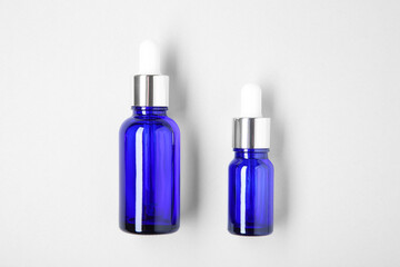 Essential oils in bottles on light background, top view