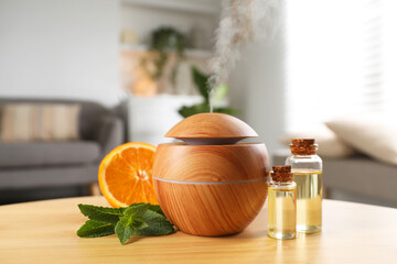 Essential oil diffuser, cosmetic products, mint and orange on wooden table at home