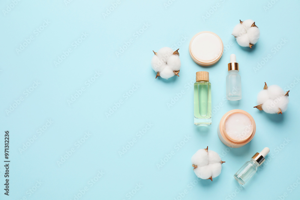 Poster different cosmetic products and cotton flowers on light blue background, flat lay. space for text