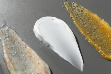 Smears of different cosmetic products on grey background, closeup