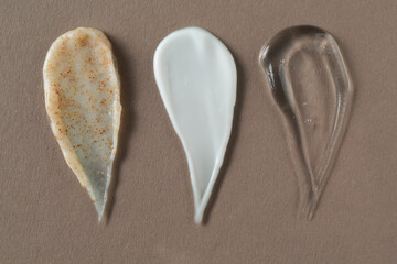 Smears of different cosmetic products on grey background, flat lay