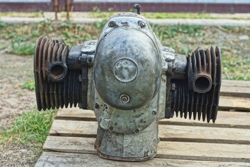 one rusty  heavy  iron  retro dirty mechanical  boxer  engine repaired from an old two-cylinder classic retro motorcycle stands on a wooden pallet during the day on the street	