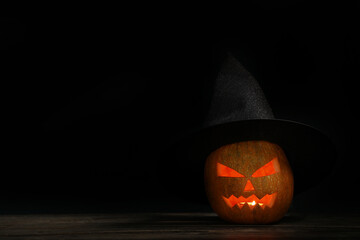 Halloween pumpkin and witch's hat on dark background