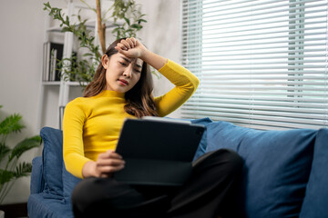 Young woman having headache while working at home on digital tablet