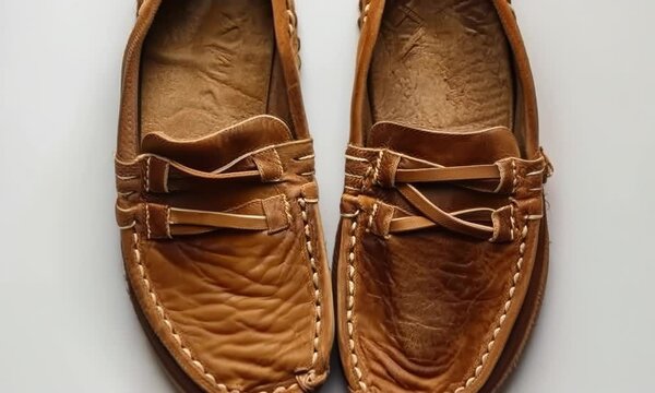Pair of stylish moccasins on white background, hyperrealistic Video