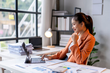 Asian businesswoman working with financial data using digital tablet and smiling