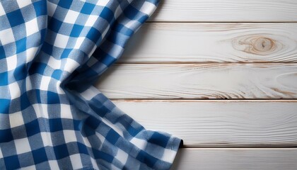 Obraz premium Blue checkered tablecloth textile on white wooden table background 