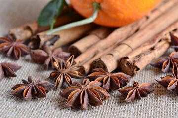 Fototapeta premium Star anise cinnamon stick orange fruit christmas thanksgiving decoration, autumn winter species and jute background, brown fall color palette, natural home decoration, kitchen food baking ingredient