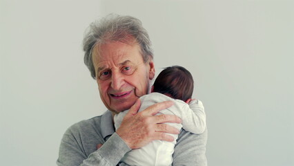 Senior man holding a newborn baby, showing affection and tenderness. The close-up highlights their emotional bond in a simple and intimate setting
