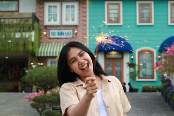 portrait of beautiful happy young asian woman holding sparklers fireworks to celebrate new year eve with garden party standing in outdoor vintage house yard