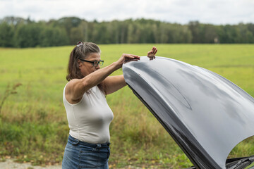 Frau schließt die Motorhaube ihres Autos