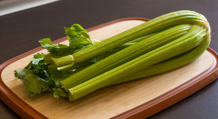 Bunch of Celery on Wooden Board Close-Up on Dark Background