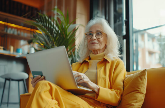 Woman sitting background modern interior holding credit card her hand while browsing web laptop