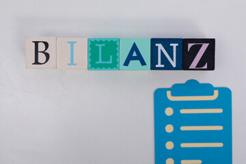 Colorful Wooden Blocks Spelling 'BILANZ' with Clipboard