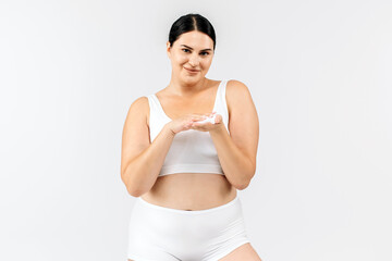 Fototapeta premium Beautiful brunette using foaming cleanser on a white background. Perfect for promoting skincare, highlighting the effectiveness and luxury of your daily cleansing product.